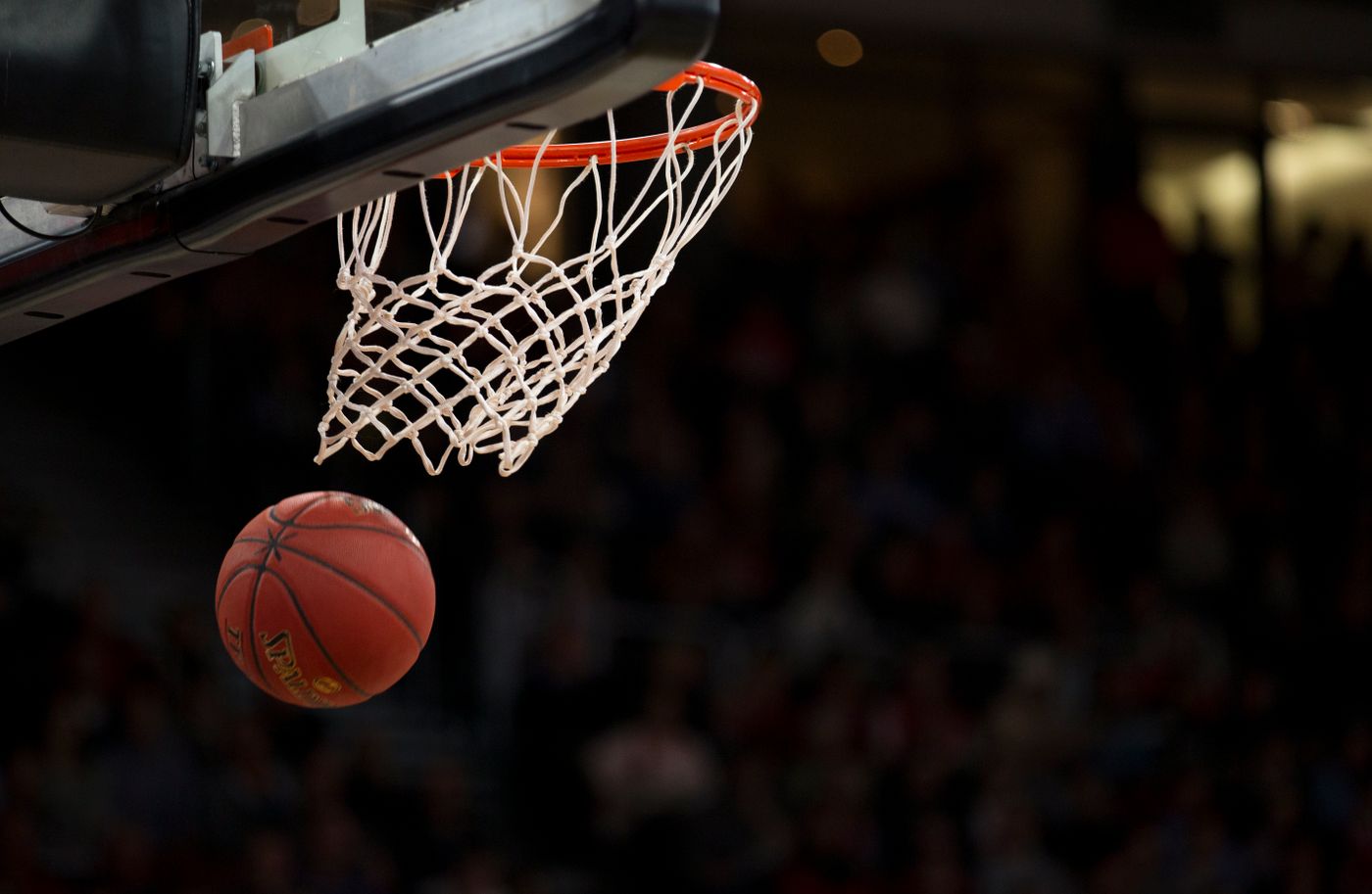 A basketball dropping through the net in a packed gym